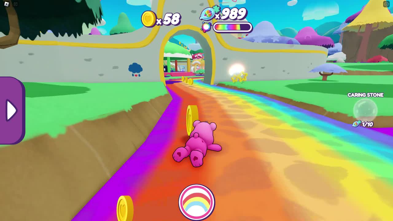 Care Bears Caring Quest on Roblox: a pink bear lies belly-down on a rainbow path leading to an arched gate in a stone wall, with gold heart coins, counters reading 58 and 989, a rainbow meter, a Caring Stone marker at 1 of 10 and a round rainbow button