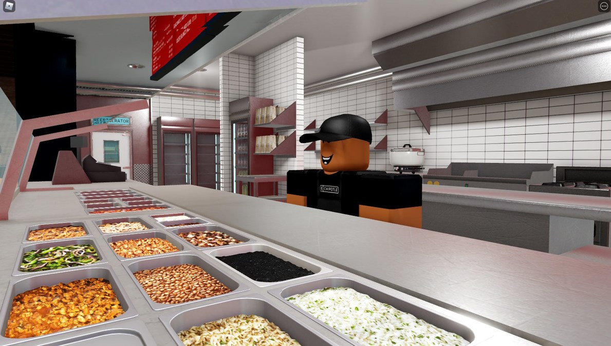 A Roblox crew member in a Chipotle shirt and cap behind the counter, with trays of rice, beans and fillings on the line in Burrito Builder