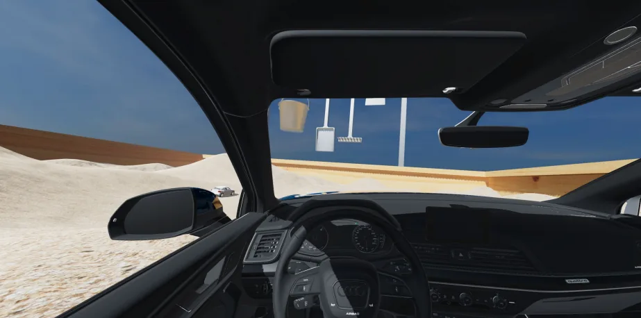 Driver's-seat view in Audi's Enter Sandbox: the Q5 dashboard and steering wheel facing sand dunes, with a giant bucket, spade and rake hanging above the sandbox wall