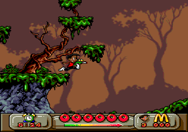 Global Gladiators for McDonald's: a boy in a red top leaps past a slime-covered tree at a cliff edge with a gun in hand, above a status bar with an alarm-clock timer, a row of red rings and McDonald's golden M