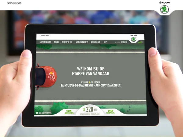 Skoda's Tour du Sofa on an iPad held in front of a TV: a Dutch welcome screen for the day's stage from Saint-Jean-de-Maurienne to Annonay Davézieux, a red Tour de France car on the road and a counter reading 220 km to the next prediction