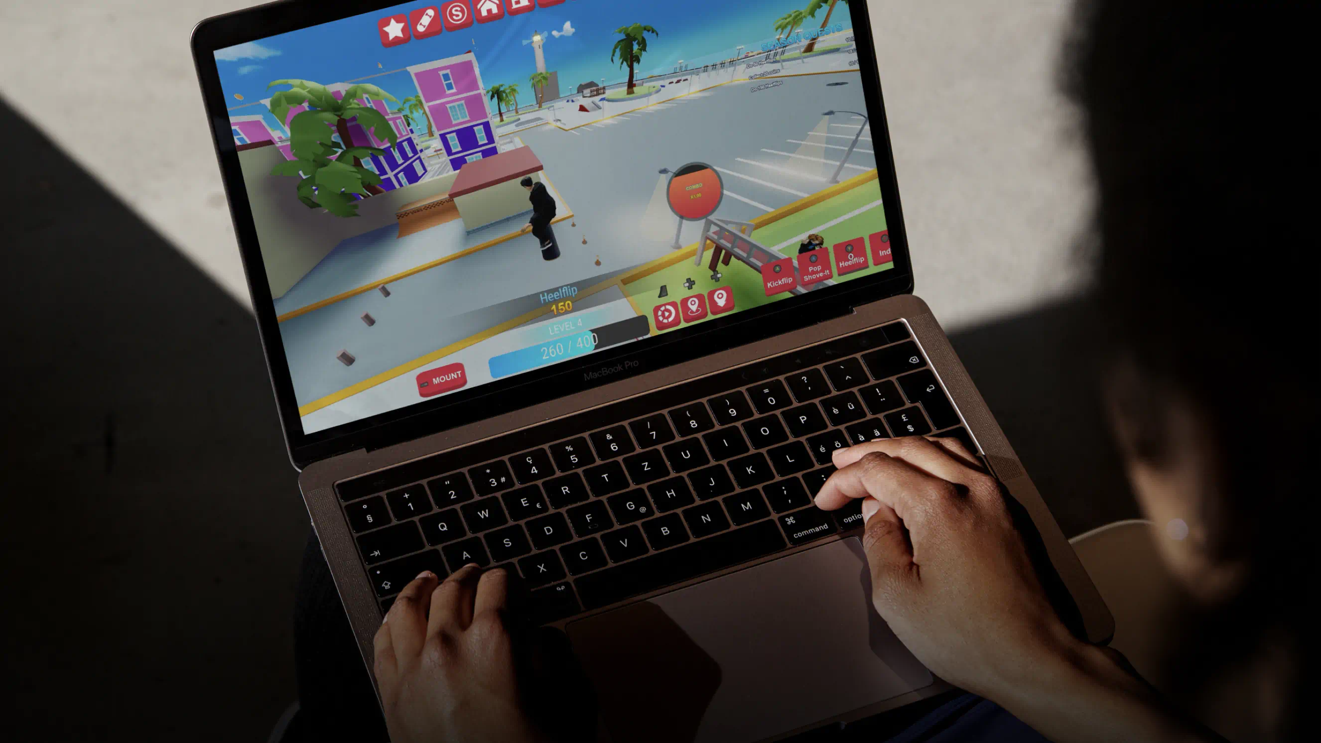 Hands on a laptop playing Vans World, the screen showing a skater, a 'Heelflip 150' score and trick buttons