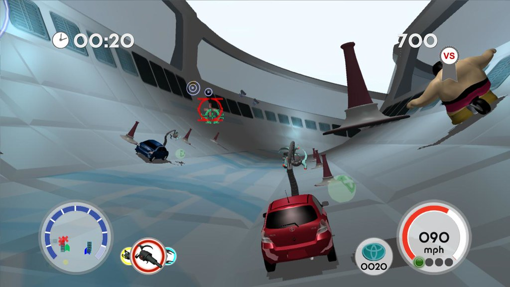 A red Toyota Yaris with a robotic arm on its bonnet races along a curved, tube-shaped track past cones, a blue rival car and a bare-chested giant on wheels in Toyota's Yaris, with a timer, a 90 mph speedometer and a Toyota-badged counter